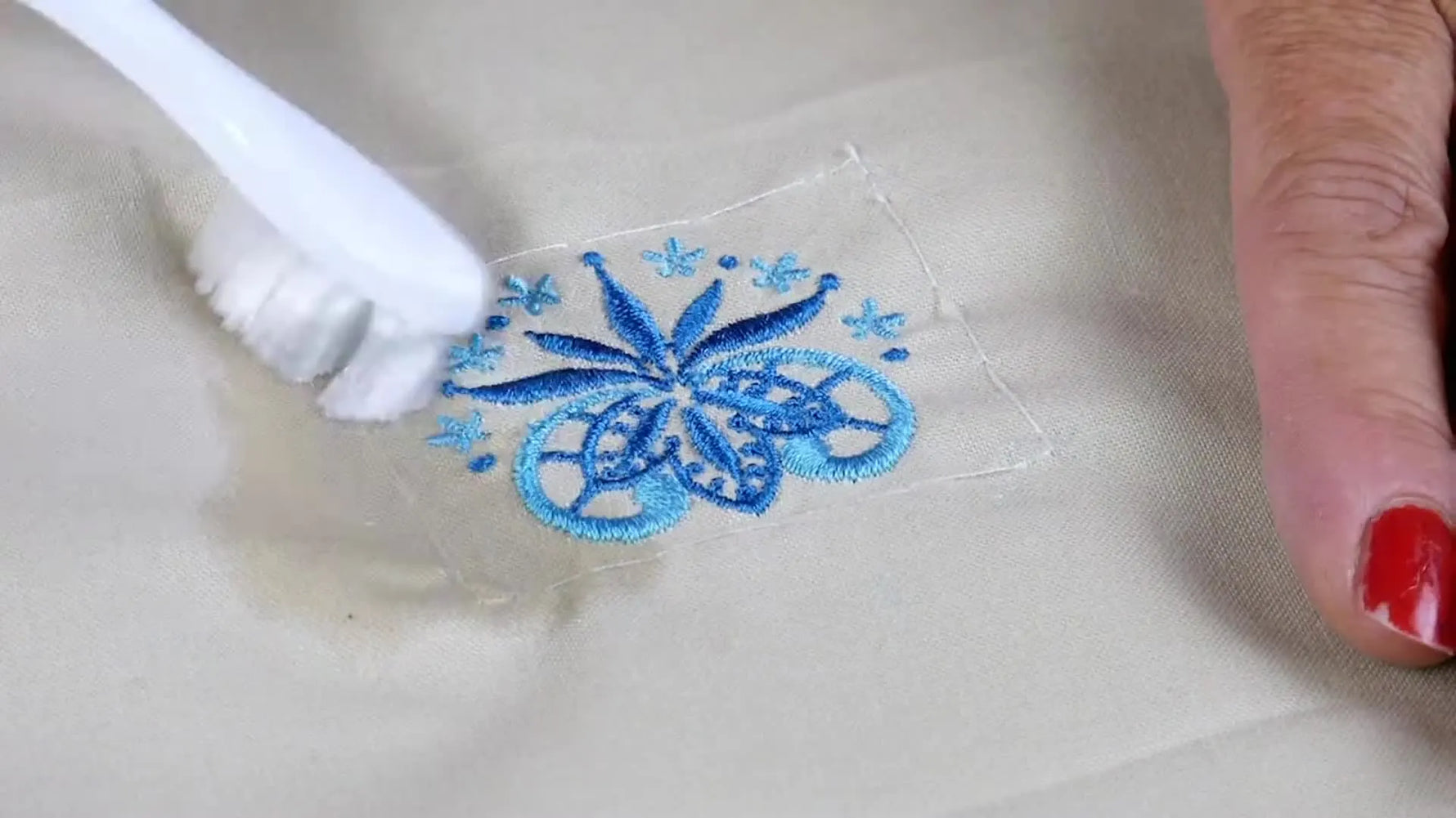 A split-screen comparison shows puckering without basting versus a flat, stable embroidery result with a water-soluble basting box.