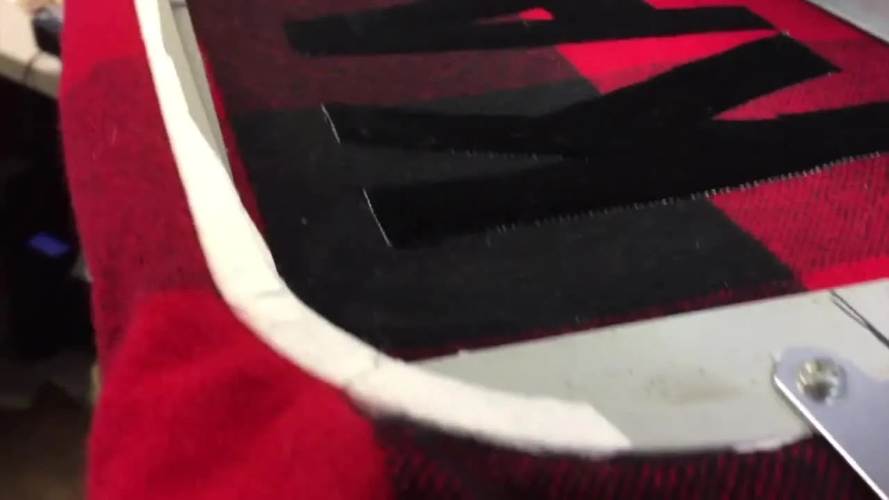 The completed velvet name appliqué is shown in the hoop after the final satin stitch, ready for trimming and delivery.