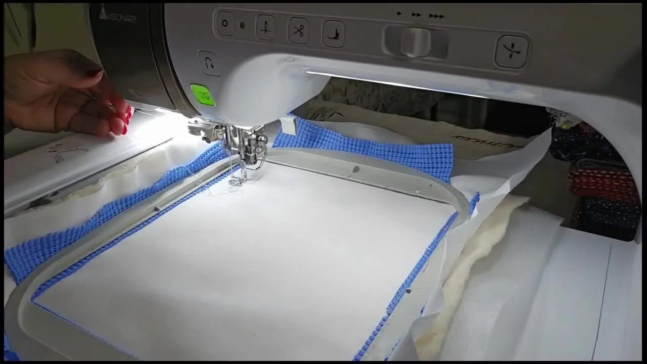 A wide view of a Baby Lock embroidery machine stitching the first butterfly motif on a hooped quilt sandwich with variegated cotton quilting thread.