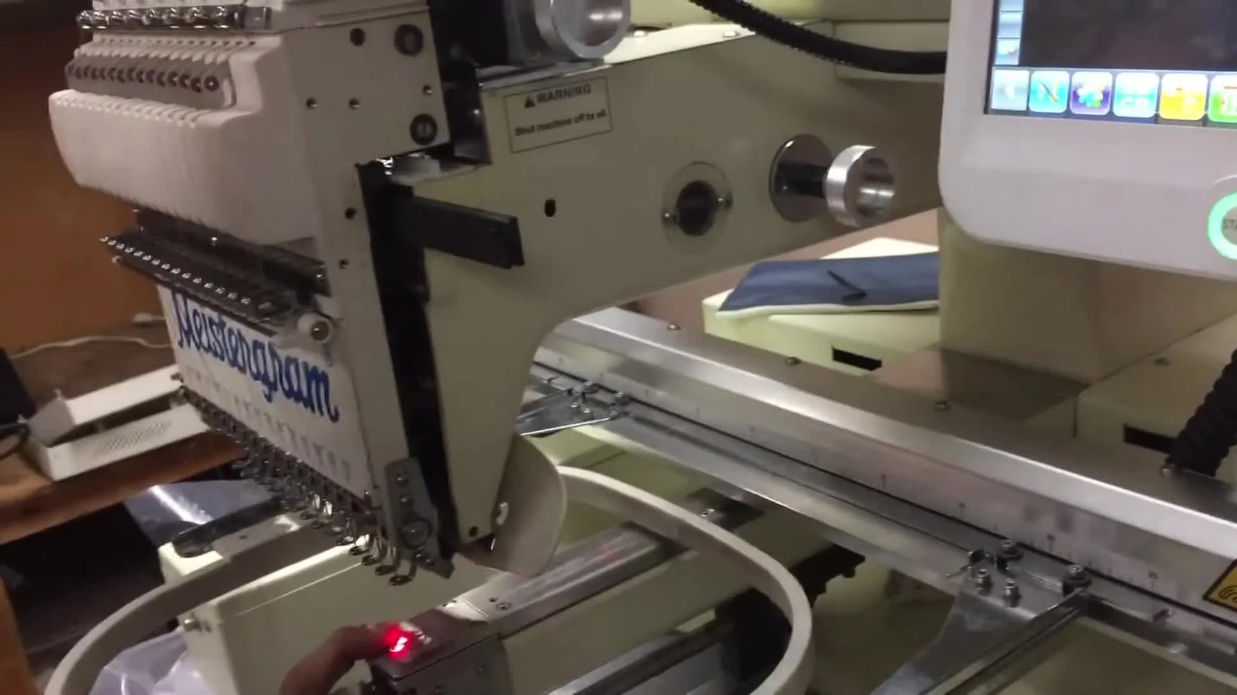 A close-up of the red laser dot landing on the magnetic hoop bracket to confirm the hoop center is correctly calibrated.
