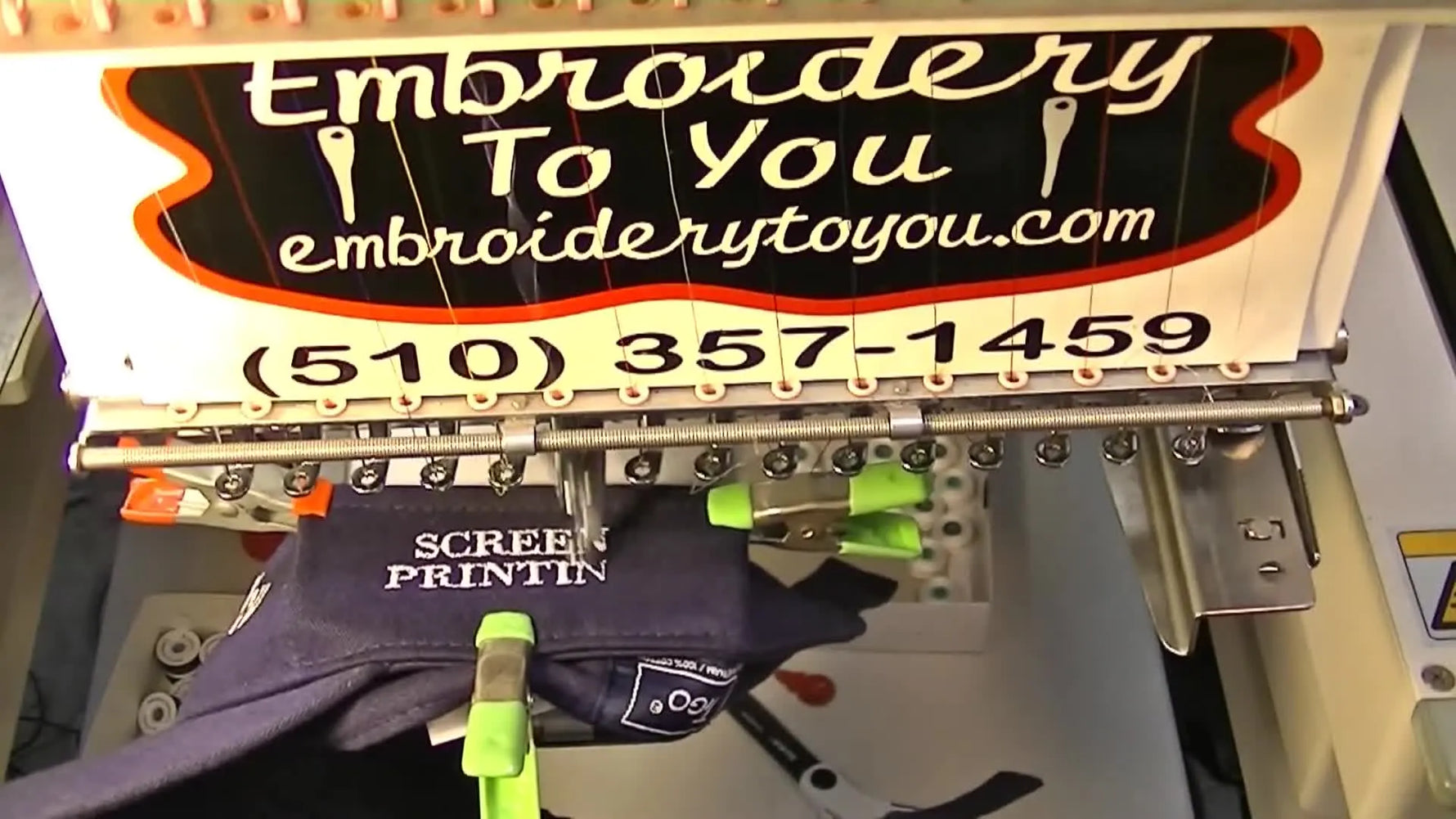 A close-up of the nearly finished “SCREEN PRINTING” embroidery on the side of a navy visor, showing clean lettering and safe clearance from the frame arms.
