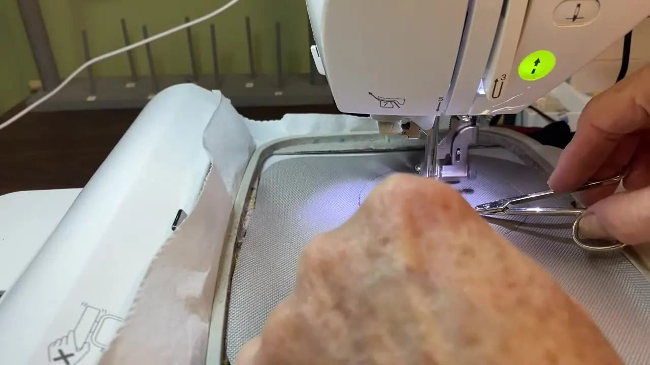 A close-up of a Fleur-de-lis design stitching out in variegated thread on a Brother PE770, showing the anchor and fill stitches in progress.