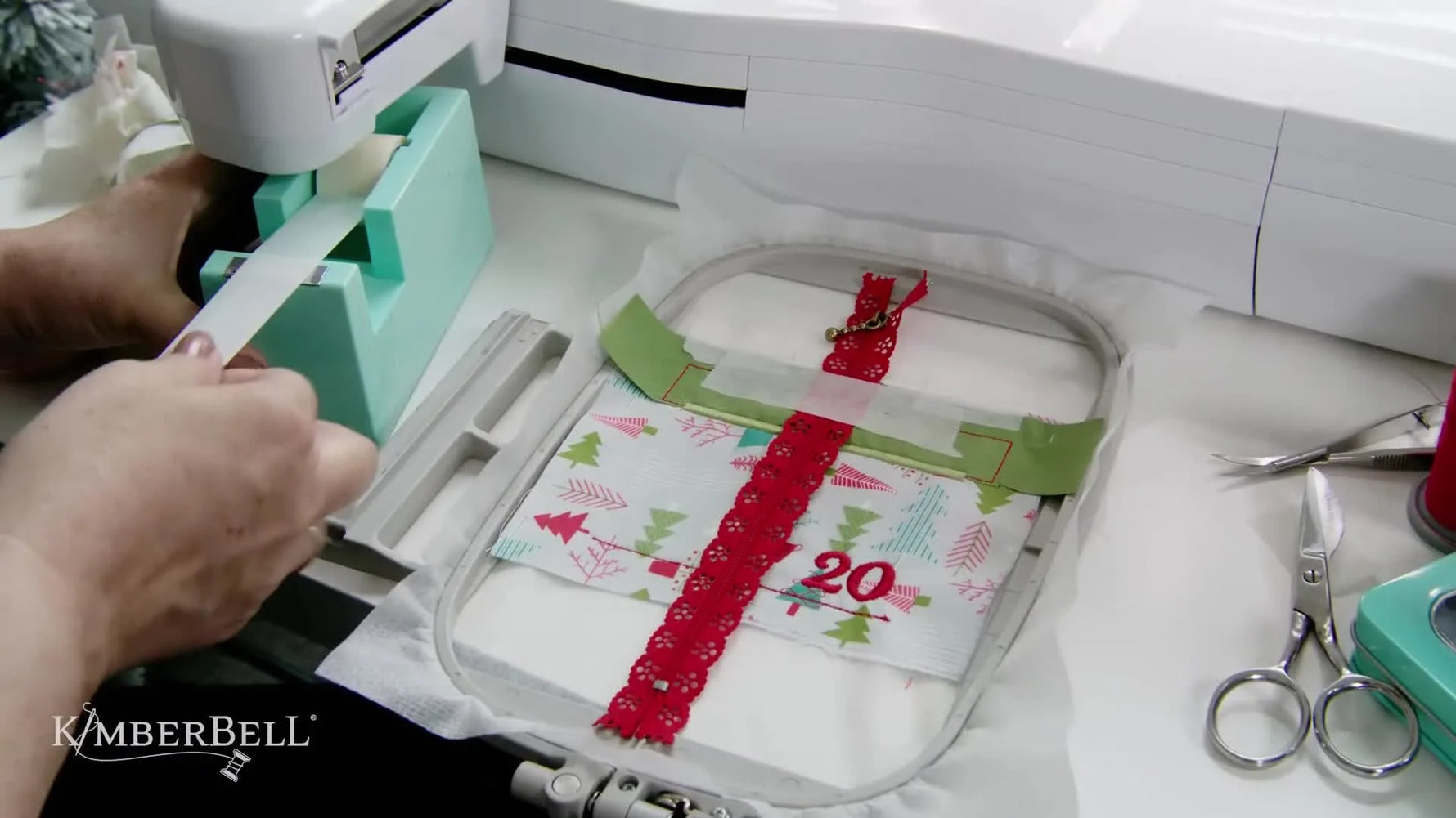 A close-up of the embroidery machine stitching a zipper tack-down line on a lace zipper during an in-the-hoop gift box pocket project.