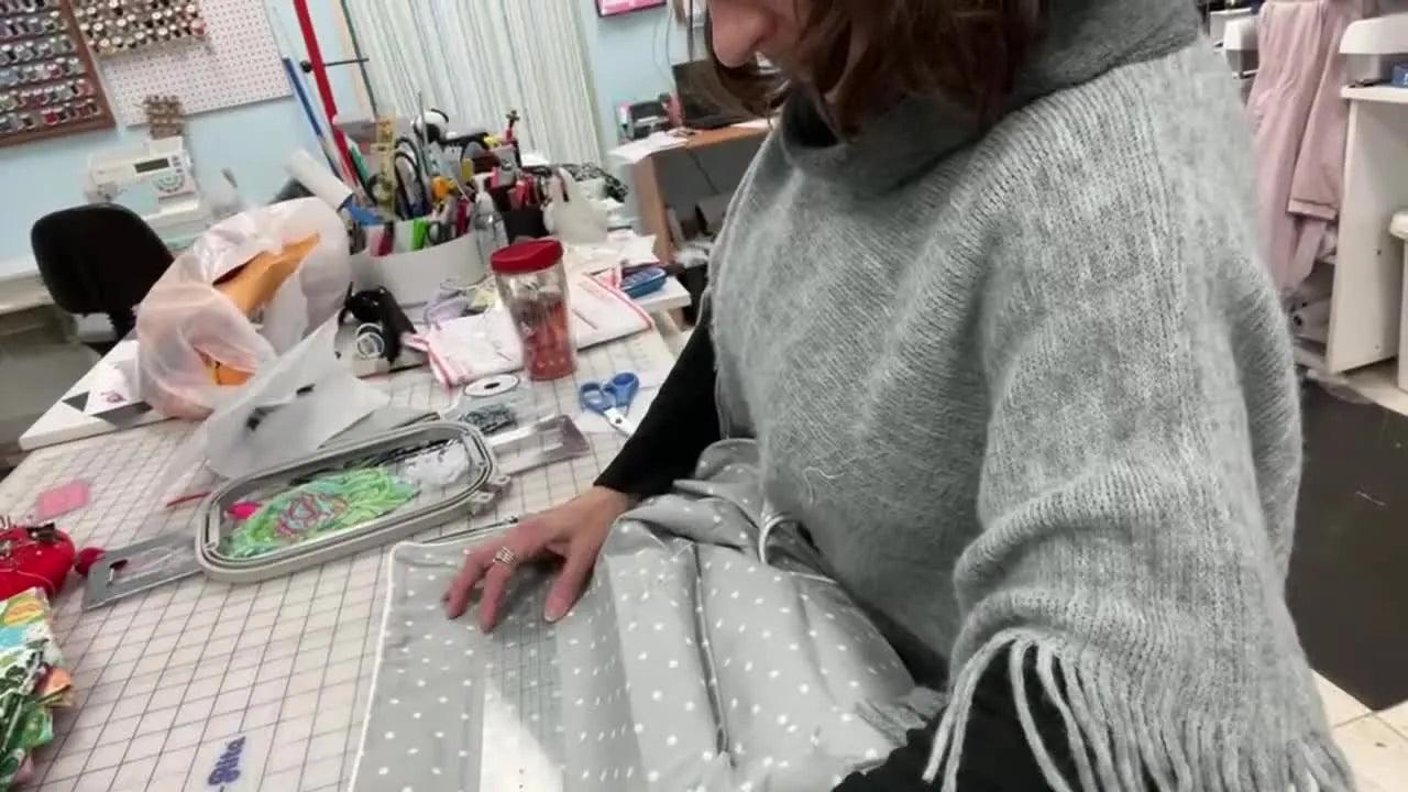 A clear ruler measures the Pottery Barn chair slipcover width while a pin marks the exact center point for embroidery placement.