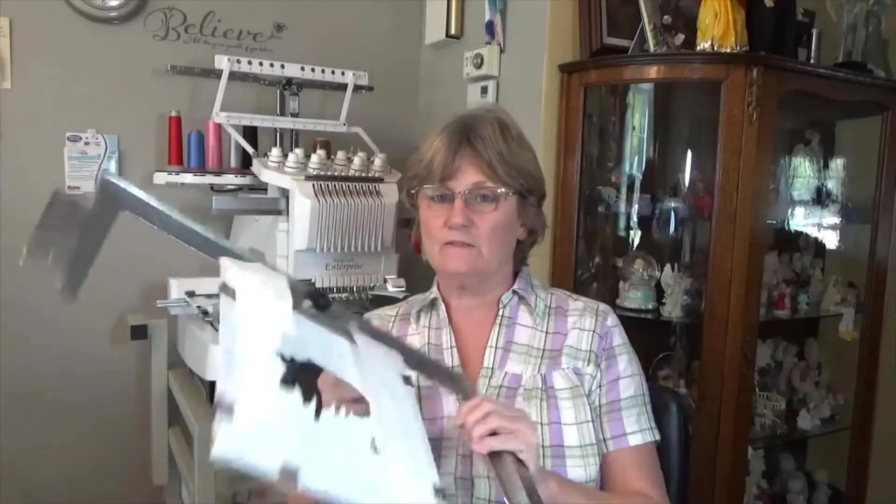 Sherry holds the Fast Frame bar and hardware used to mount an open-arm frame on a Baby Lock Enterprise 10-needle machine.