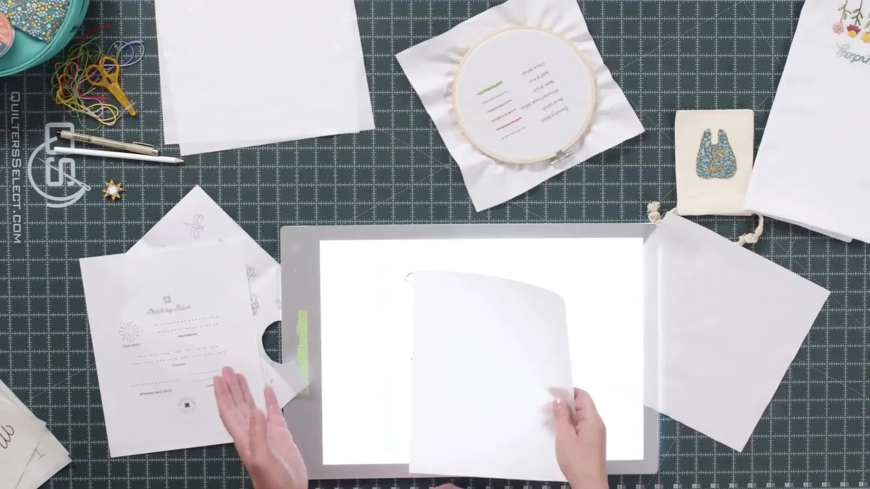Hands tracing the word 'Happy' onto a sheet of Peel-n-Stick, which is placed over a printed template on a light box.