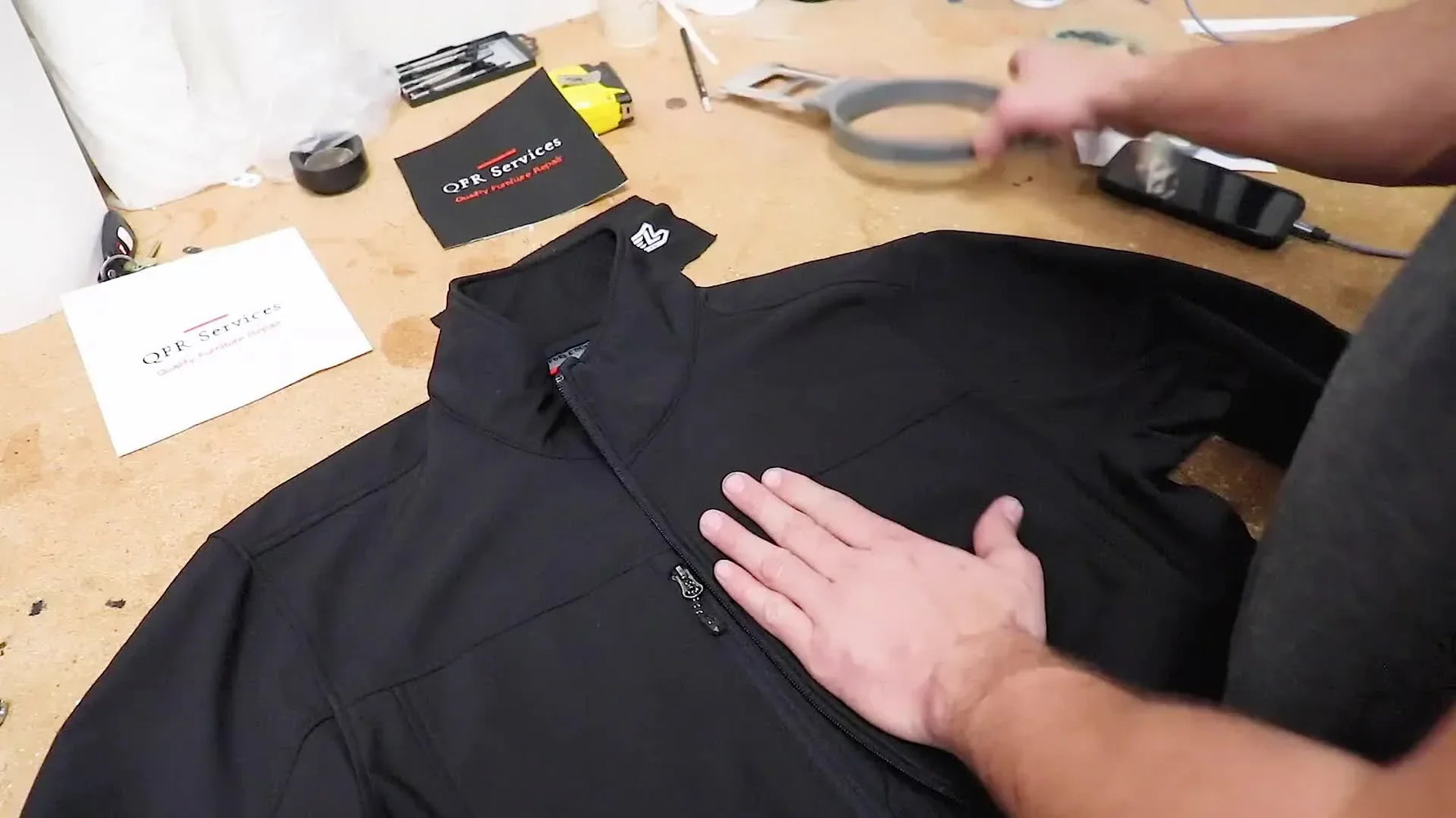Man hooping a black jacket onto an embroidery machine's C-size hoop.