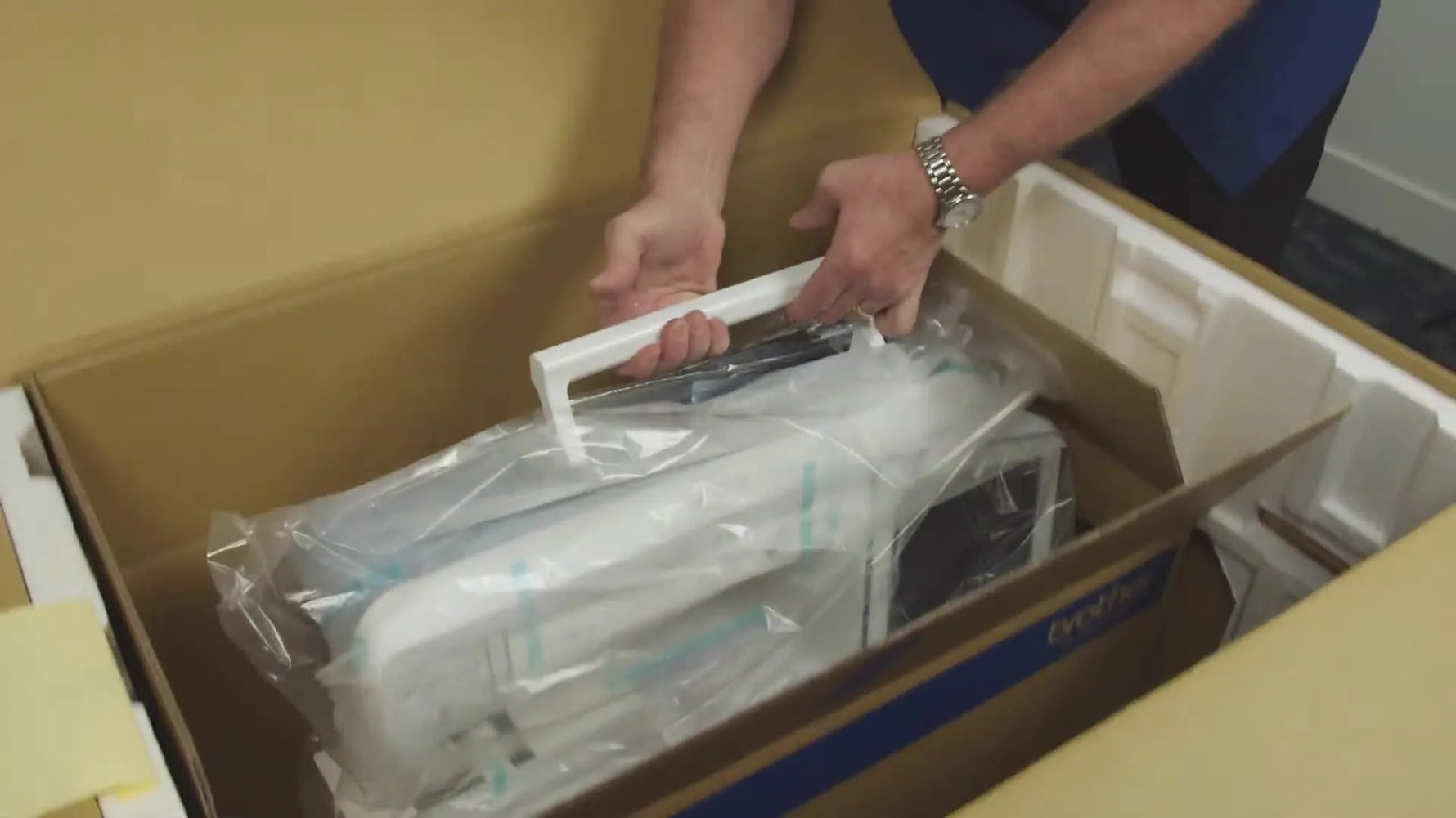 A close view of the Brother Luminaire XP2 being lifted out of its packaging by the built-in handle, showing the moment where safe handling matters most.