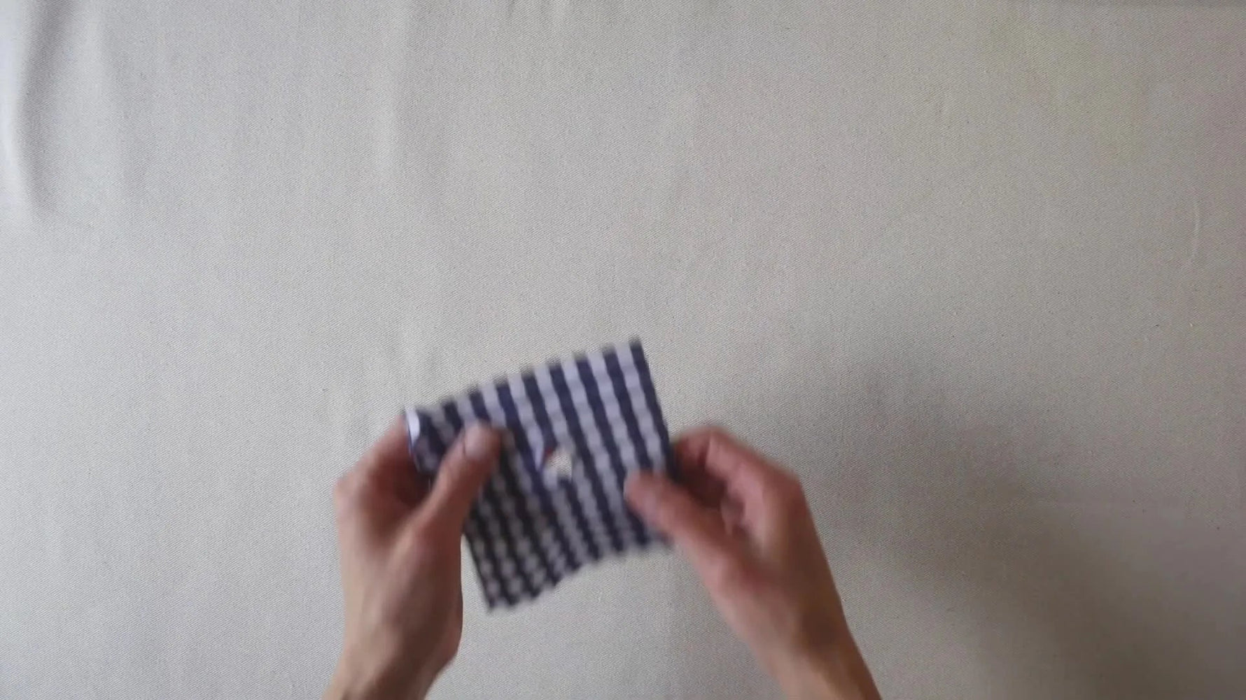 Close-up of a blue and white gingham fabric swatch with a small hole in the center.