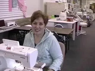 Woman smiling in front of an embroidery machine, holding two finished Easter favors.