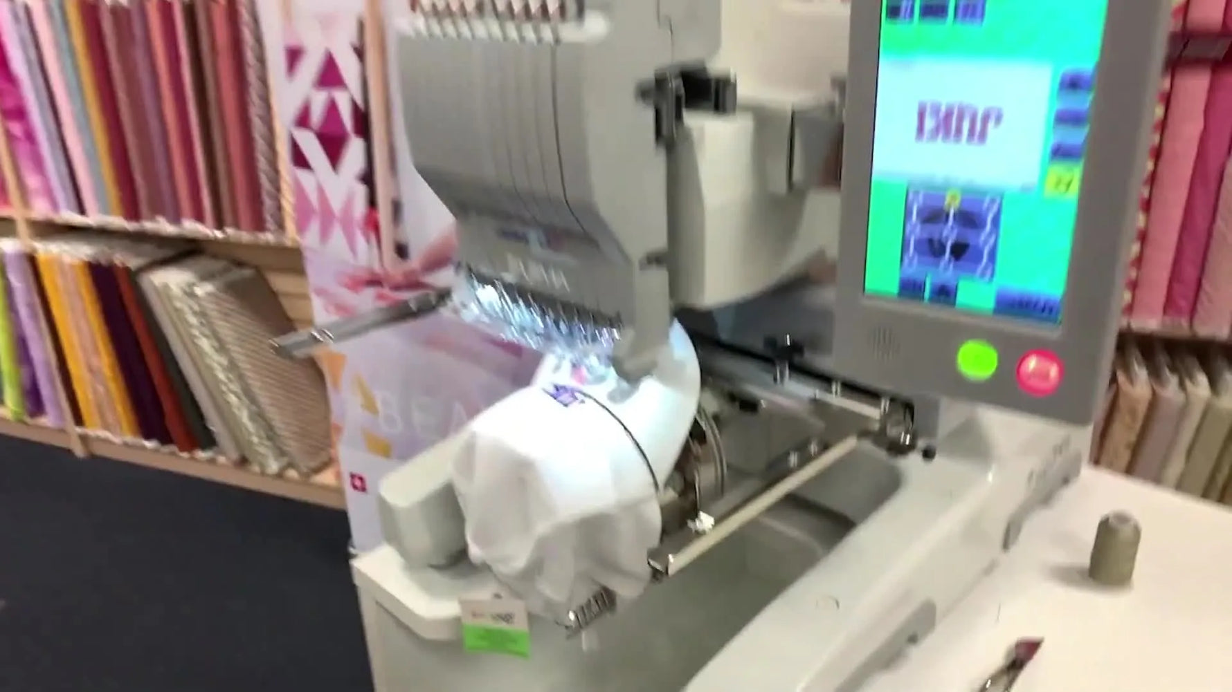 A close-up of a red laser crosshair projected onto a white cap, showing precise embroidery placement before stitching.