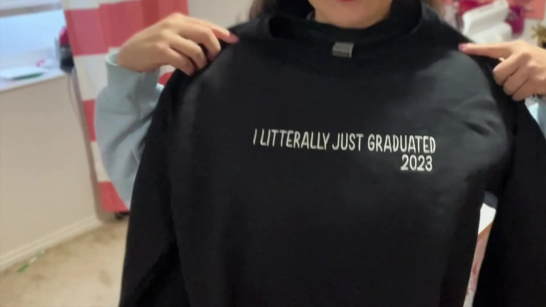 The creator holds up the finished sweatshirt and realizes the embroidered word is misspelled, capturing the exact moment every embroiderer dreads.