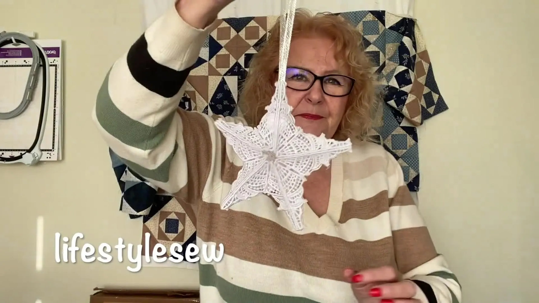 A finished 3D white free-standing lace Christmas star ornament is held up and rotated to show its structure and hanging ribbon.