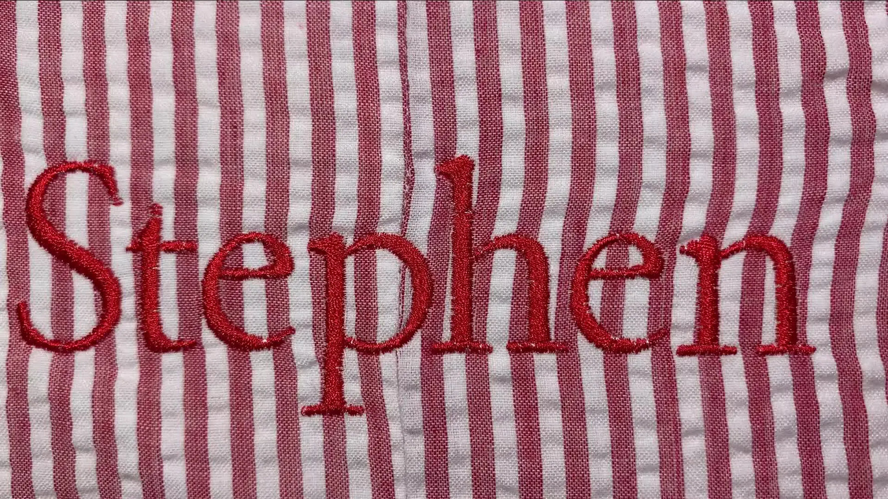 Close-up of embroidered name 'Stephen' on red and white striped fabric