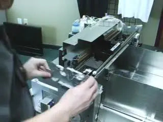 A technician aligns and seats the large metal side panel onto the embroidery machine head carriage during reassembly.