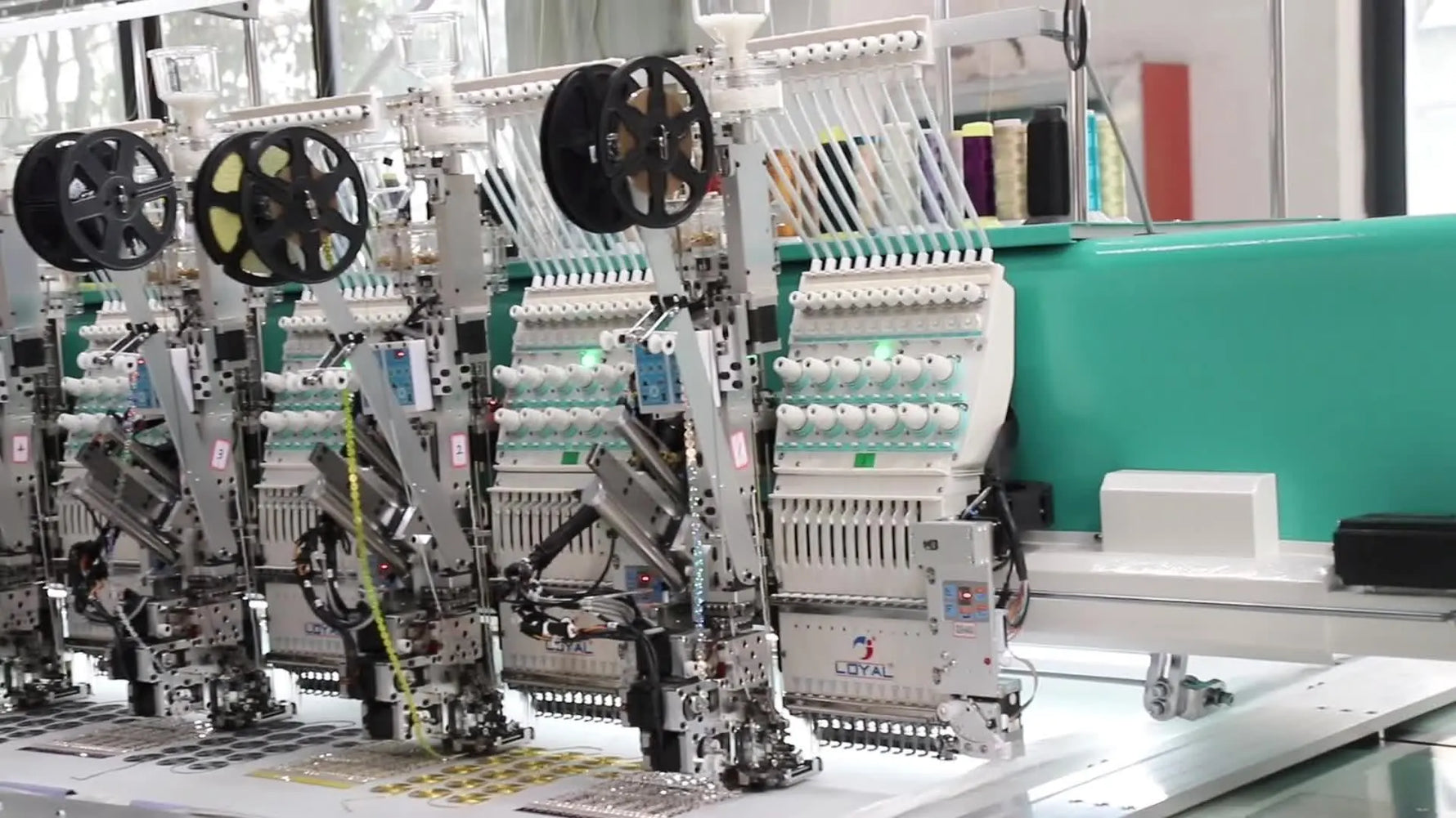 A perspective view down a long row of embroidery heads shows the scale and coordination required for mass-production stitching.