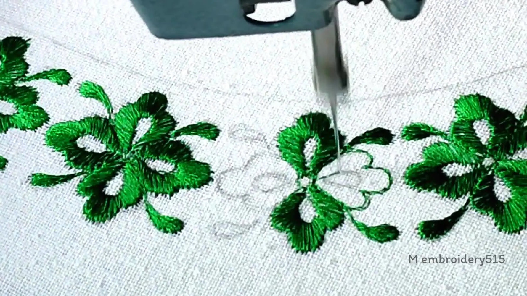 Embroidery machine with gold thread adding accent to a green flower center.