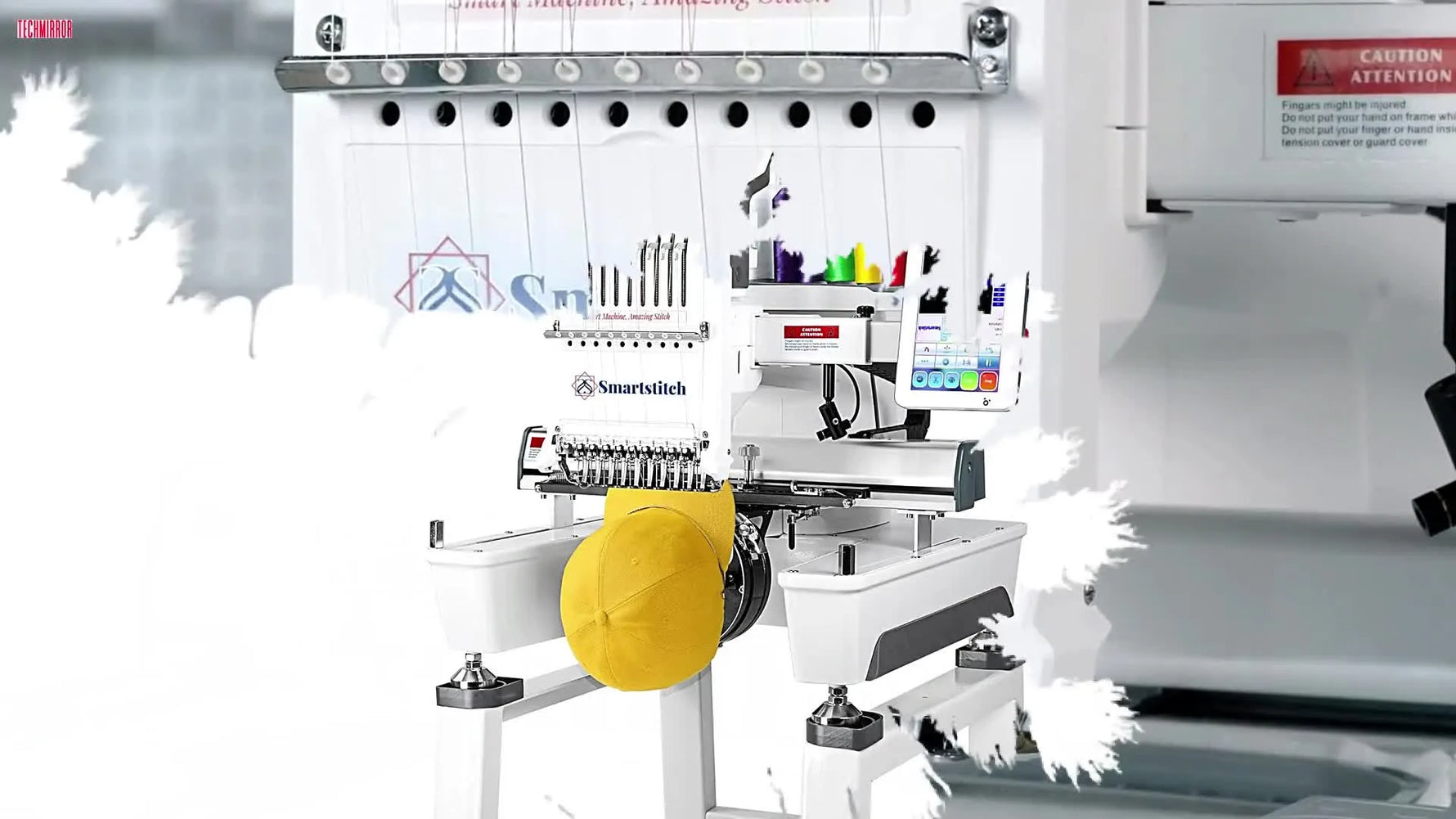 A full-profile studio shot of the SmartStitch S-1001 with a cap loaded, showing the machine body, screen, and thread stand.