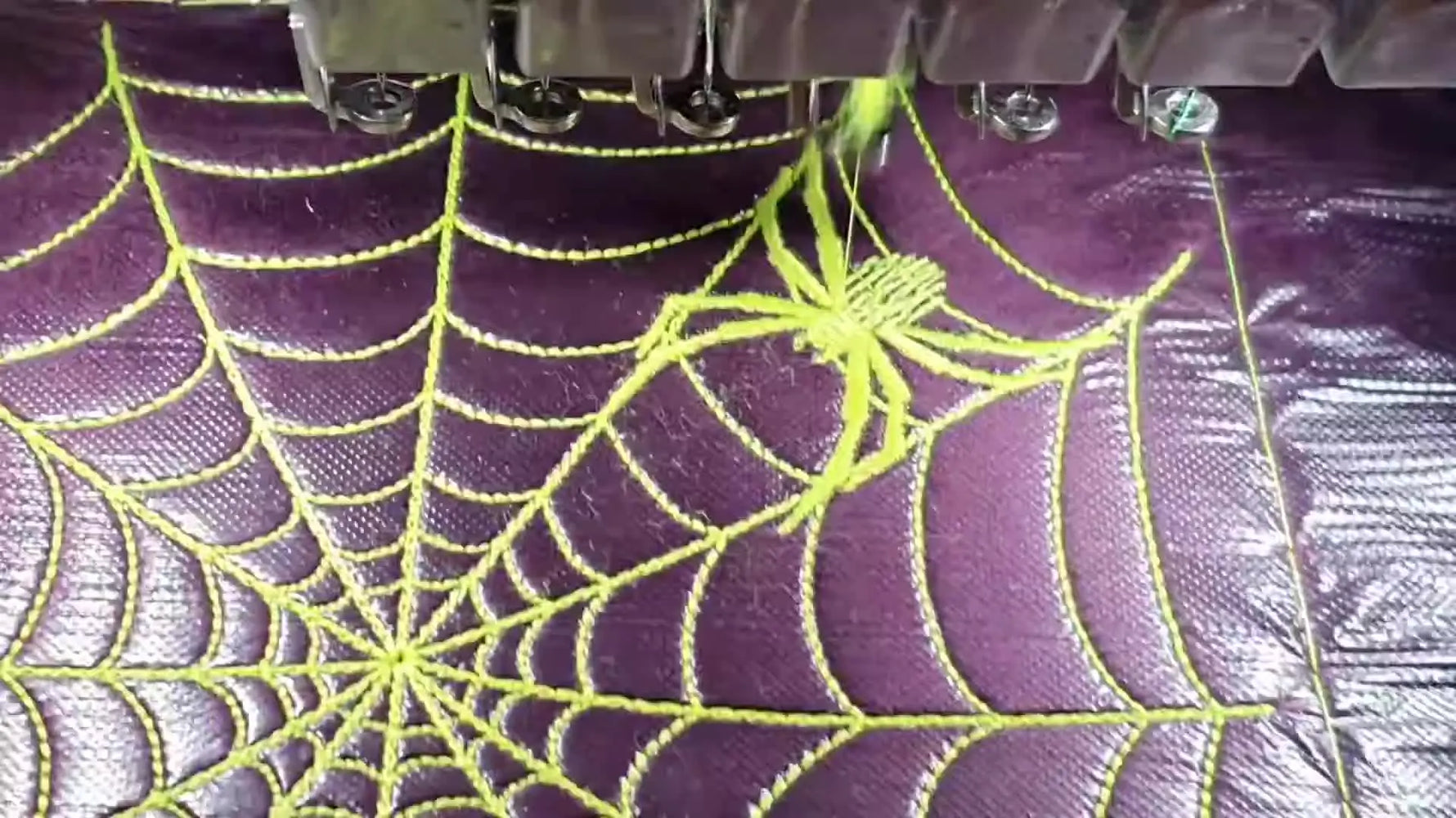 A finished purple pillow shows a bright neon spiderweb with a stitched spider motif in the upper-right quadrant.