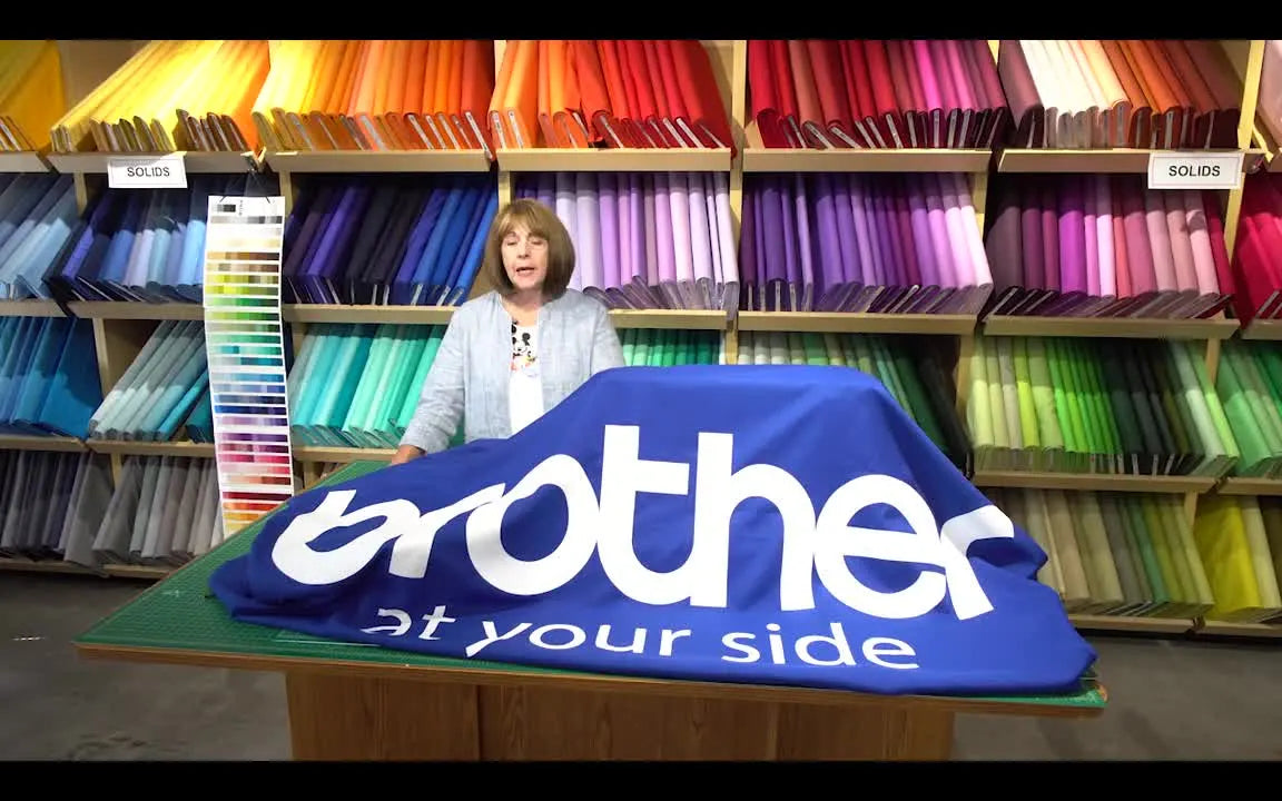 Linda stands beside a covered Brother machine while explaining the refundable deposit deadline and the pre-order bonus package.