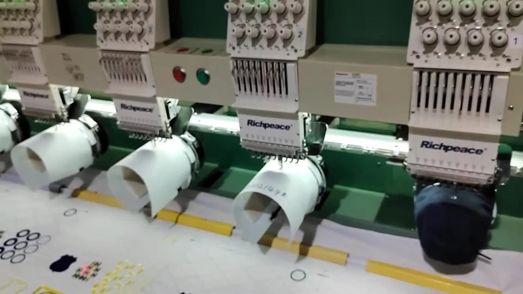 Multiple embroidery heads stitch simultaneously on cap fronts, illustrating stable high-volume cap production.