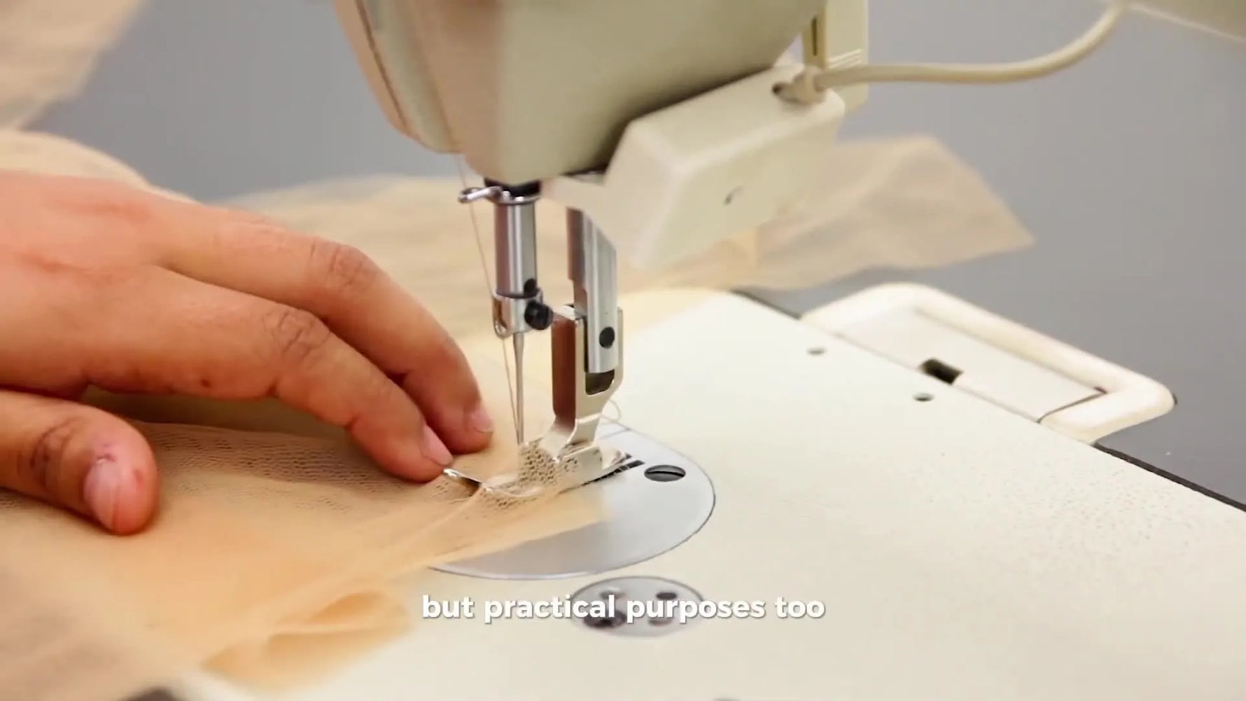 A multi-needle commercial embroidery machine stitches a logo onto a purple baseball cap mounted on a cap driver.