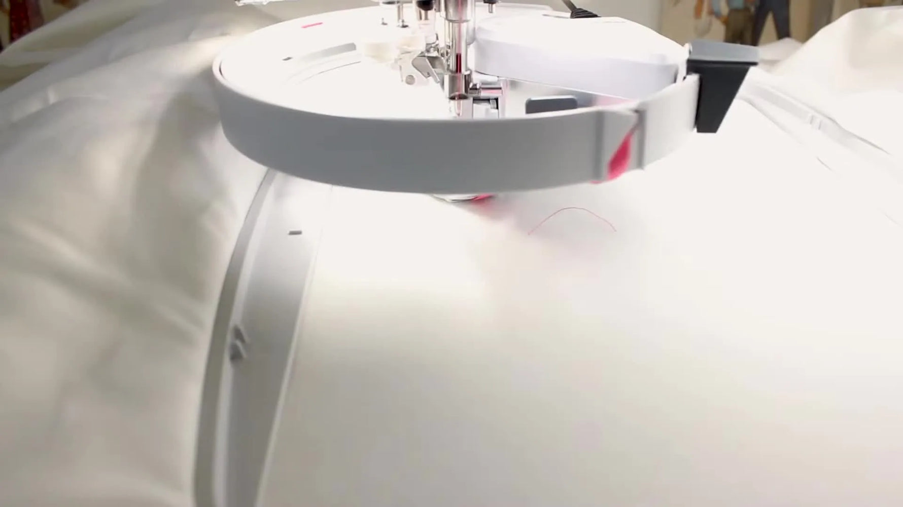 Close-up of the Designer EPIC 2 stitching a pink ribbon design while the ribbon attachment rotates to form 3D letters.
