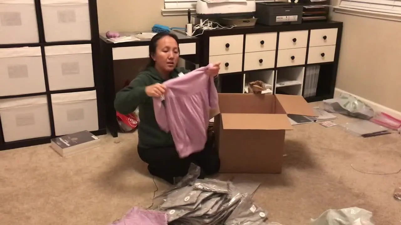 Zoe holds up a lavender bubble sweatshirt—one of the specialty blanks she plans to turn into high-margin personalized embroidery orders.