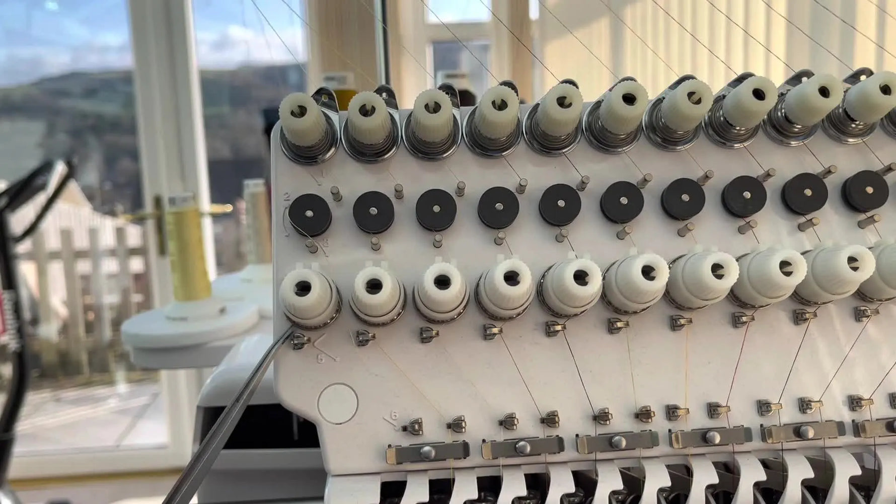 An extreme close-up shows the thread seated correctly in the groove of the main tension wheel on a Happy Japan HCS3 head.