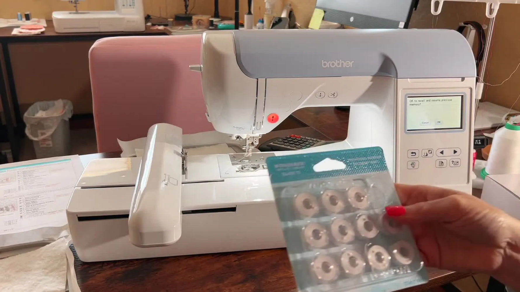 A close-up of WonderFil Class 15 pre-wound bobbins being held up as the practical fix for a Brother PE800 bobbin pick-up failure.