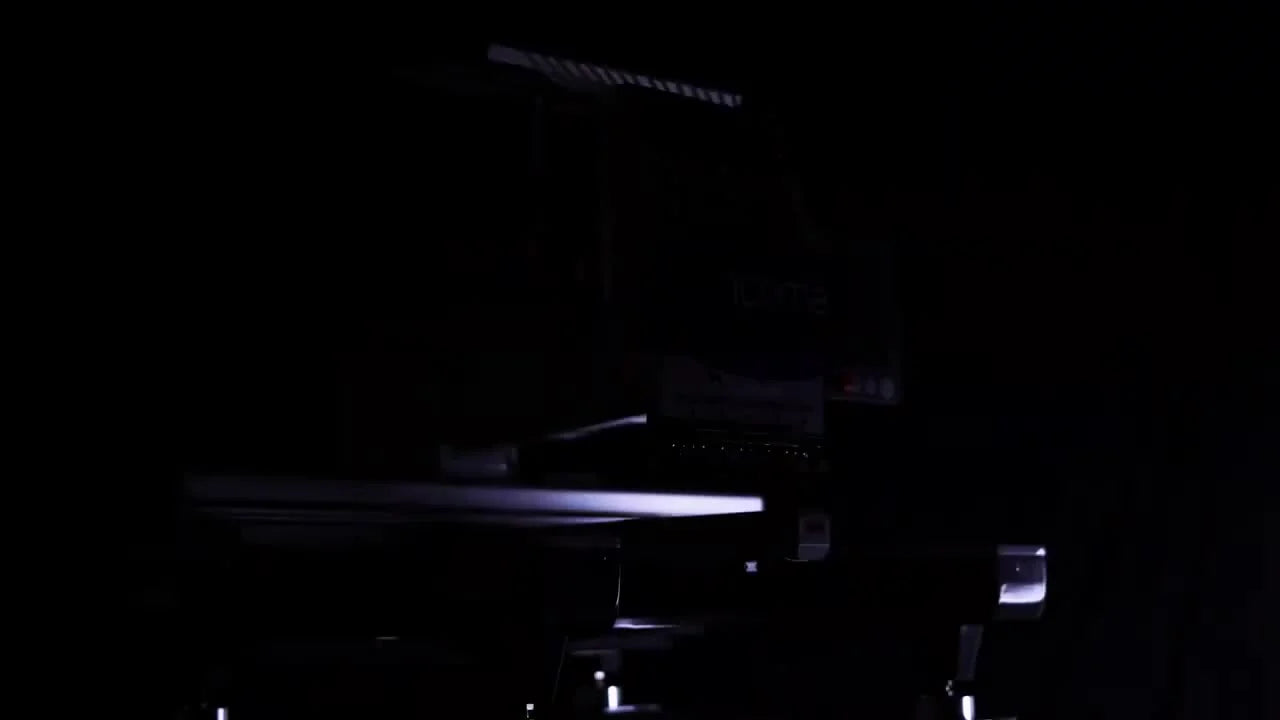 A dramatic studio shot of the Ricoma SWD 15-needle head and thread rack, lit against a black background.