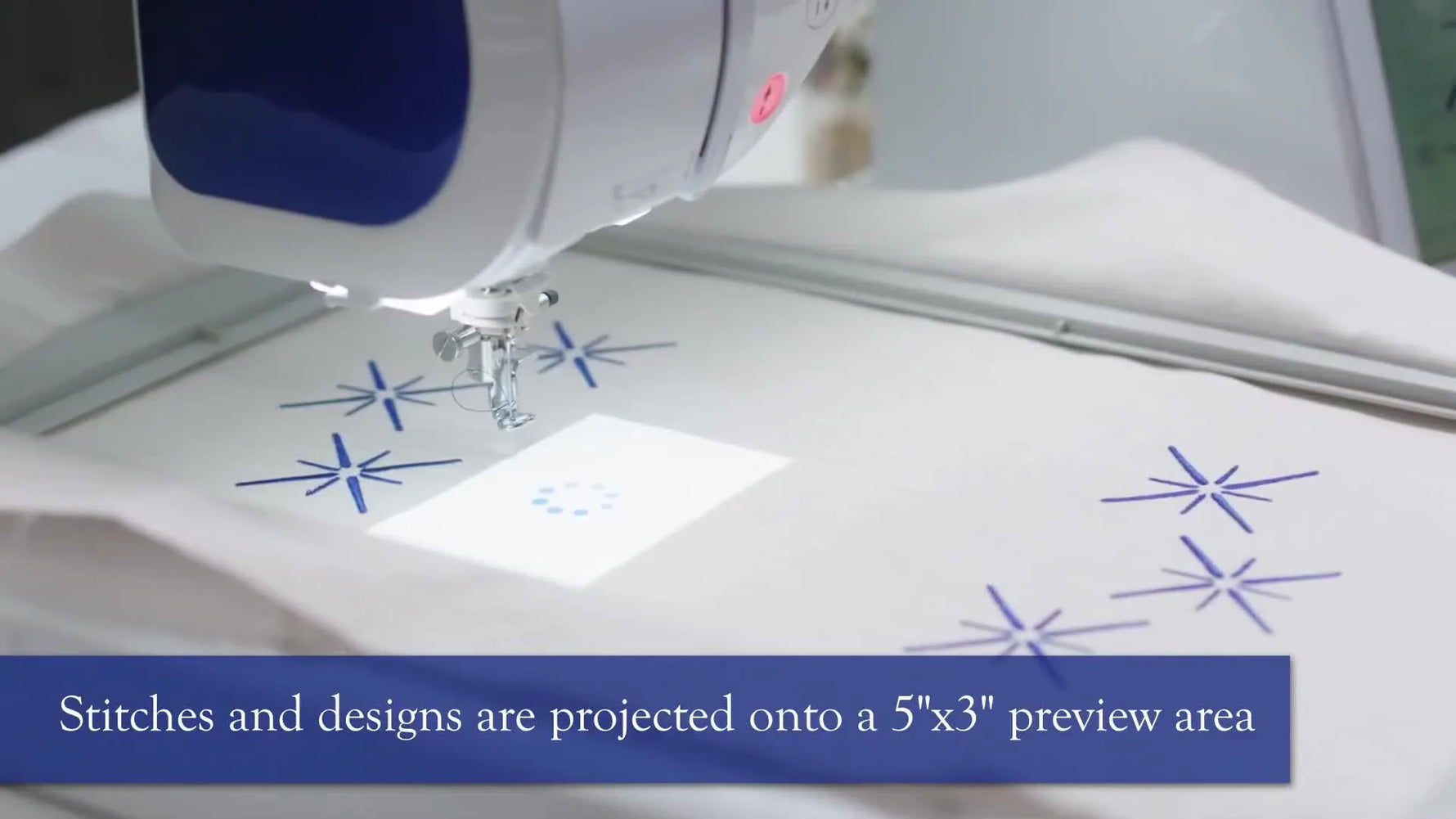 A close-up of the Brother Luminaire projecting a blue snowflake design onto hooped white fabric for precise embroidery placement.