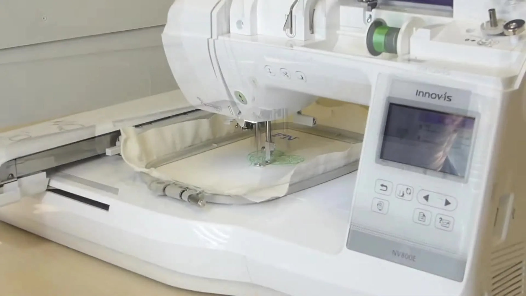 Close-up of the Brother Innov-is 800E actively stitching a green heart design on calico.