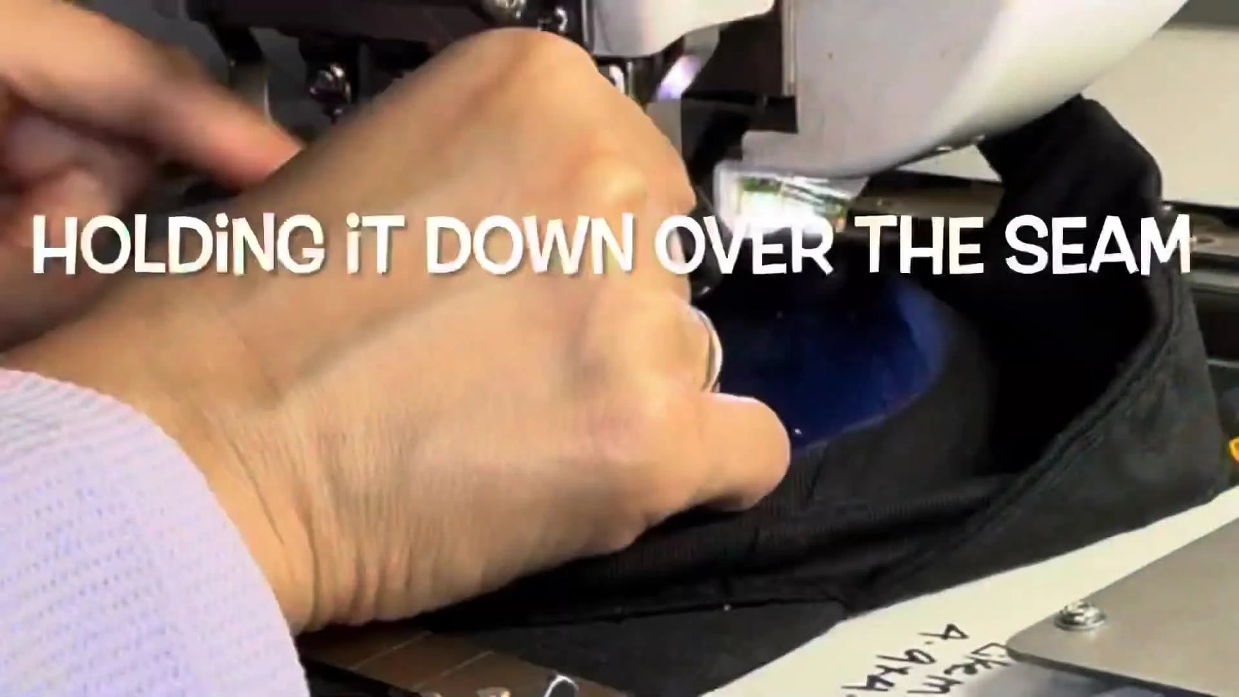 A close-up shows a finger holding a structured hat down near the needle while the Janome MB-4 stitches—an effective but risky workaround for hat flagging.