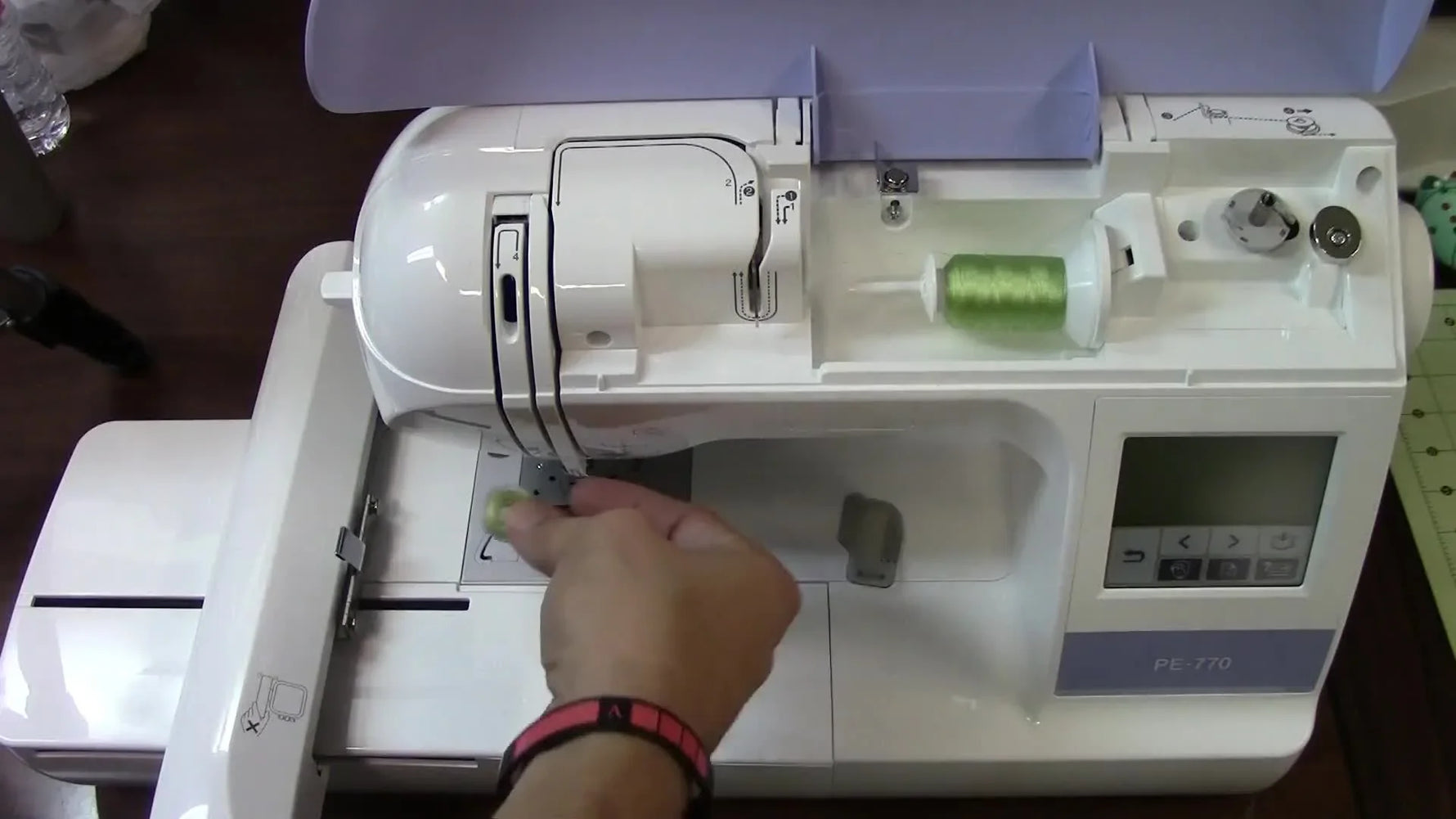 A close-up of the Brother PE-770 stitching green thread onto yellow duck cloth inside a standard 5x7 hoop.