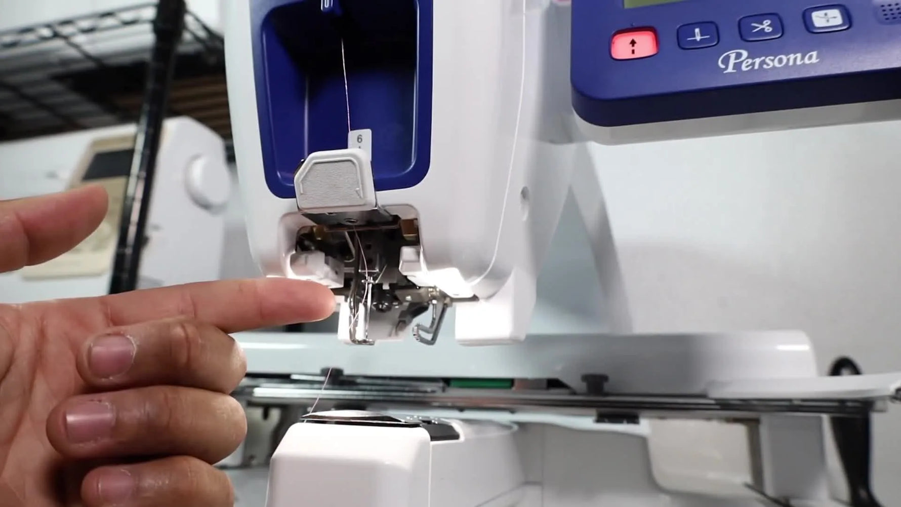 A close-up of the Brother PRS100 Persona control area as the automatic needle threader button is pressed to lower the threading mechanism.