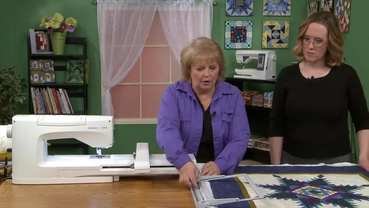A quilter demonstrates a specialized metal hoop clipped onto a quilt border for fast, screw-free re-hooping.