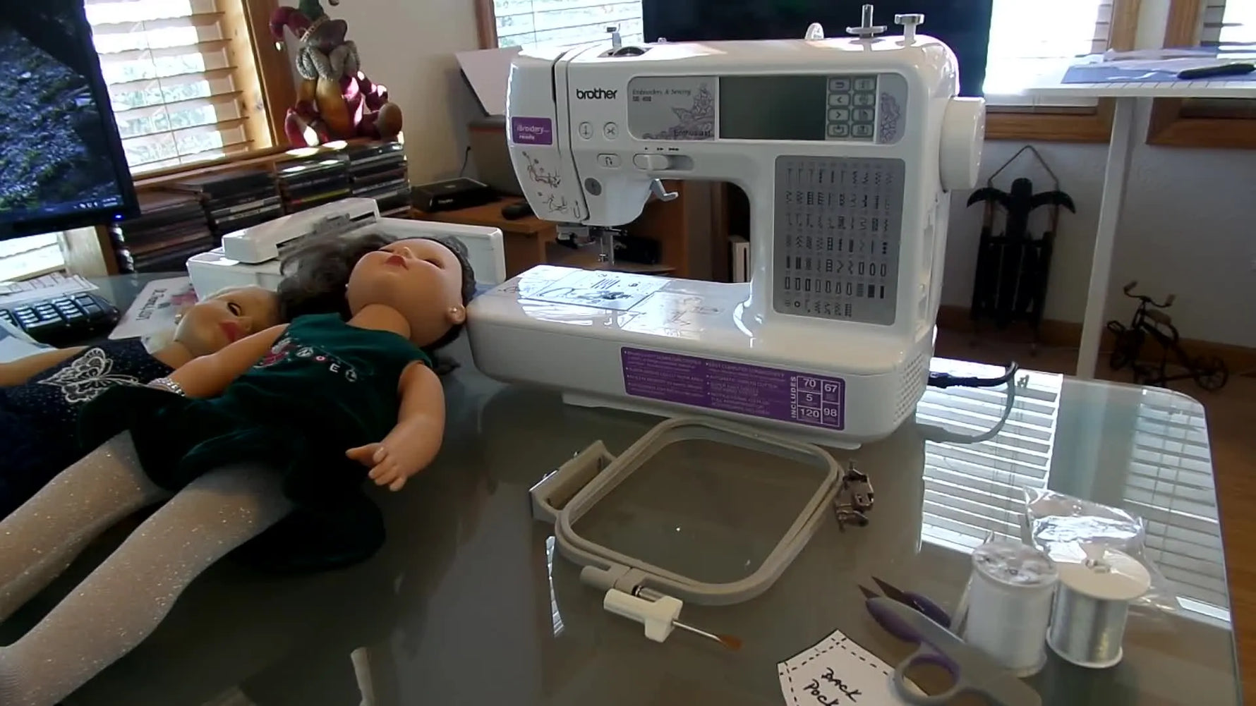 A wide shot of the Brother SE-400 on a table with thread spools and doll projects, setting the stage for a beginner embroidery setup.