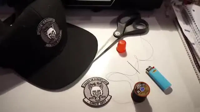 Table with hat, patch, scissors, needle, thread, lighter, and thimble