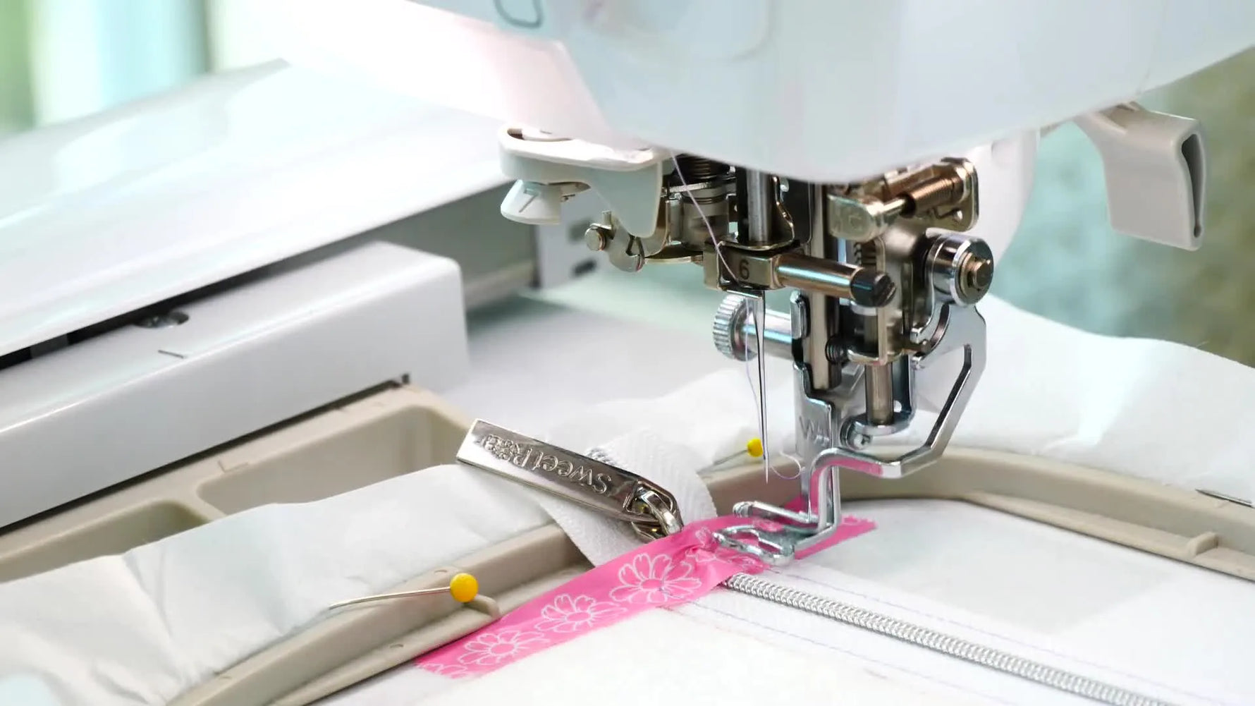 A close-up of the embroidery machine stitching a taped zipper inside a 4x4 hoop, showing the exact moment where most ITH zipper projects succeed or fail.
