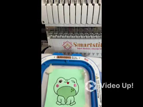 A winking frog bag tag is stitched cleanly on mint vinyl while still held flat in a 5.5" magnetic hoop, ready for backing and final outline.
