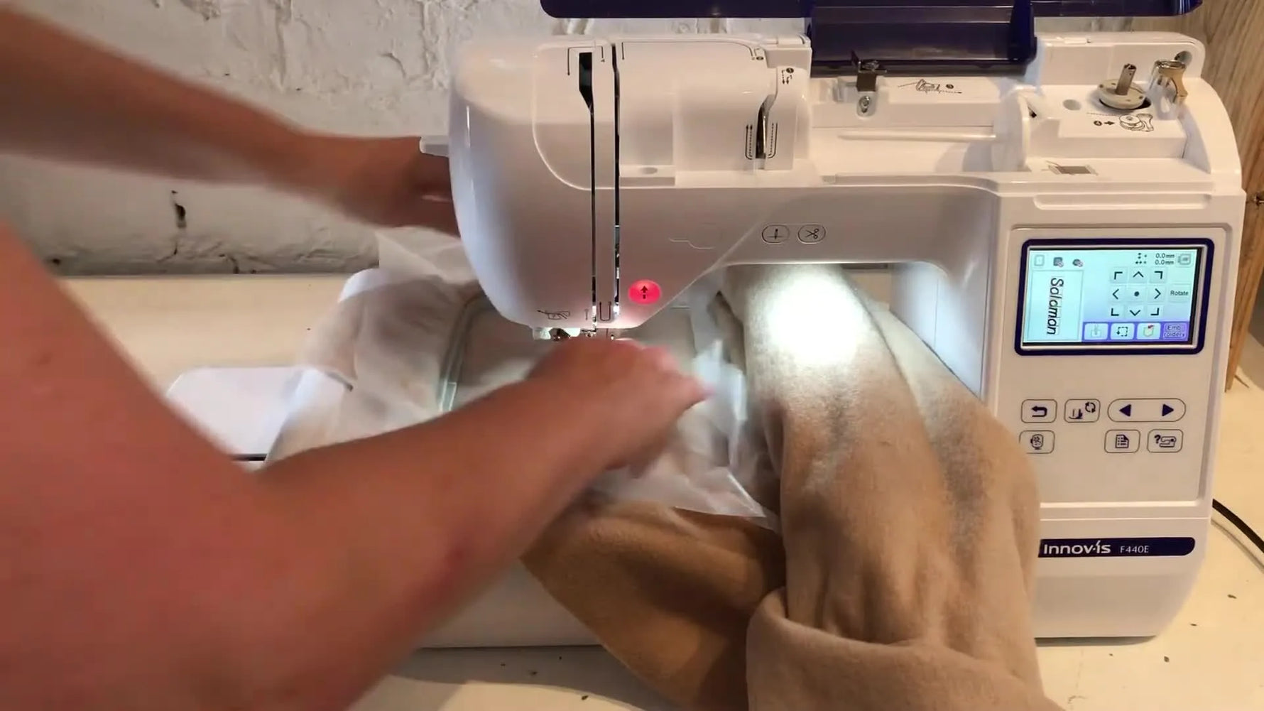A wide view of the Brother Innov-is F440E with a sweatshirt rolled to the right, creating a clear tunnel around the needle area before stitching.