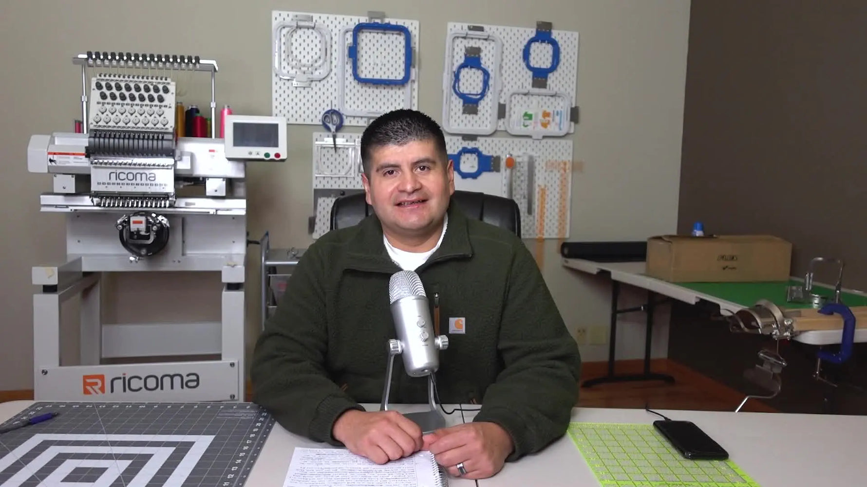 A home embroidery business setup with a multi-needle machine beside a hooping station, showing the kind of workflow that turns practice into paid production.