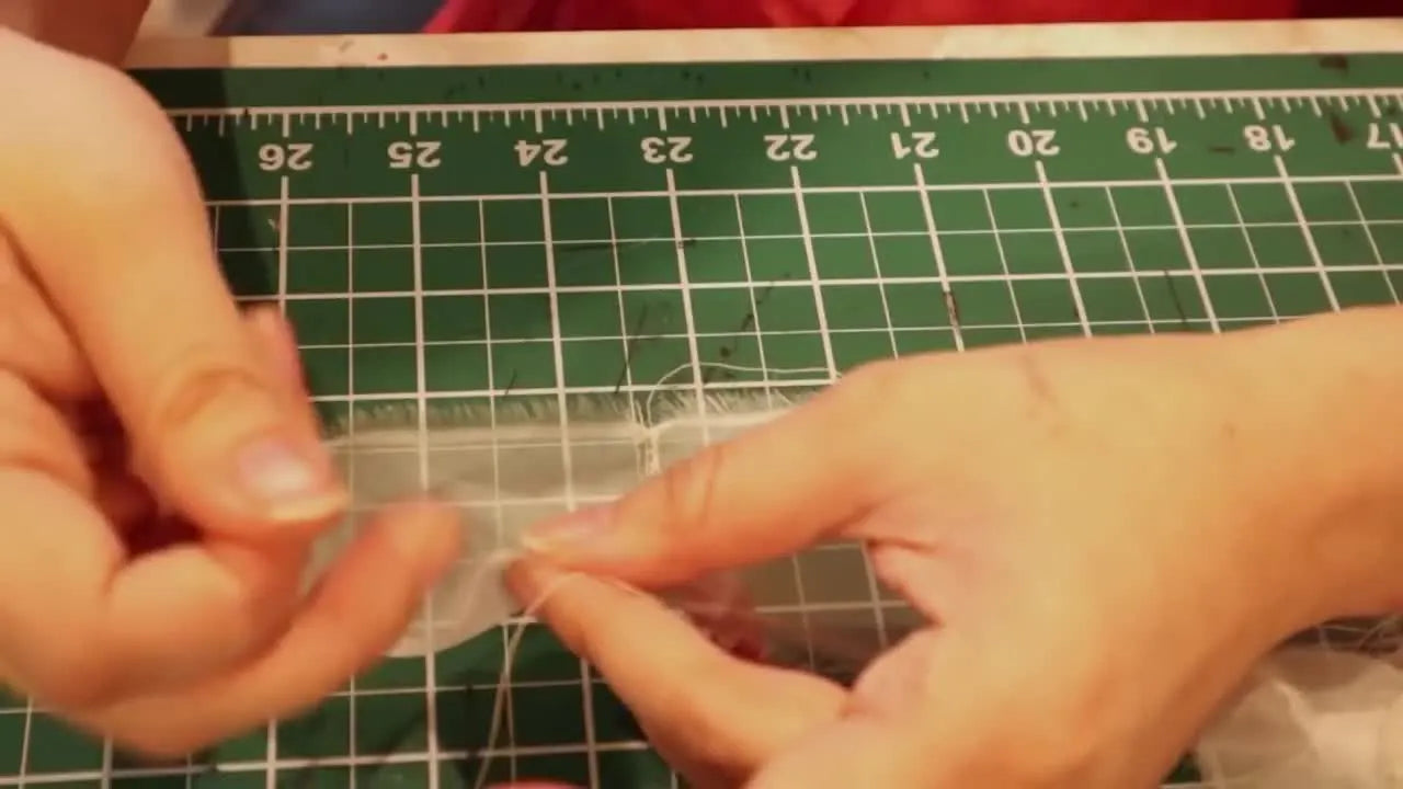 The finished pale pink bergère hat is fully decorated with organza trim, white feathers, and red flowers, ready for a costume reveal.