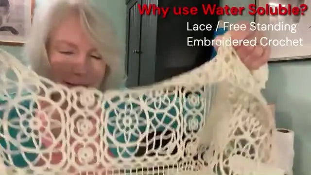 The host holds up a large lace jacket made entirely of thread, demonstrating why water-soluble stabilizer is essential for standalone lace projects.