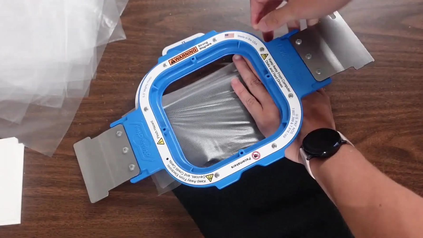 A close-up of a magnetic hoop snapping onto a thick beanie cuff with topping in place, ready for clean text embroidery.