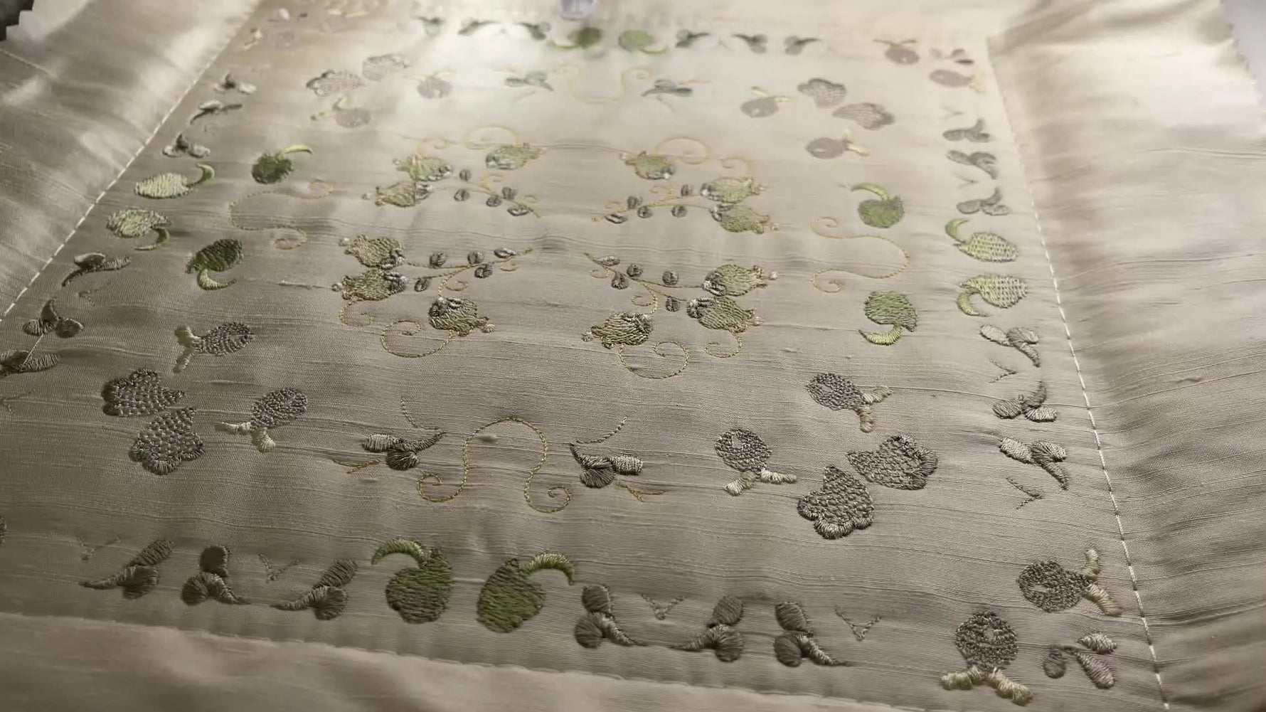 An overhead view of the nearly finished Jacobean quilt block inside the 260×260mm hoop, showing dense embroidery, blended greens, and crisp framing.