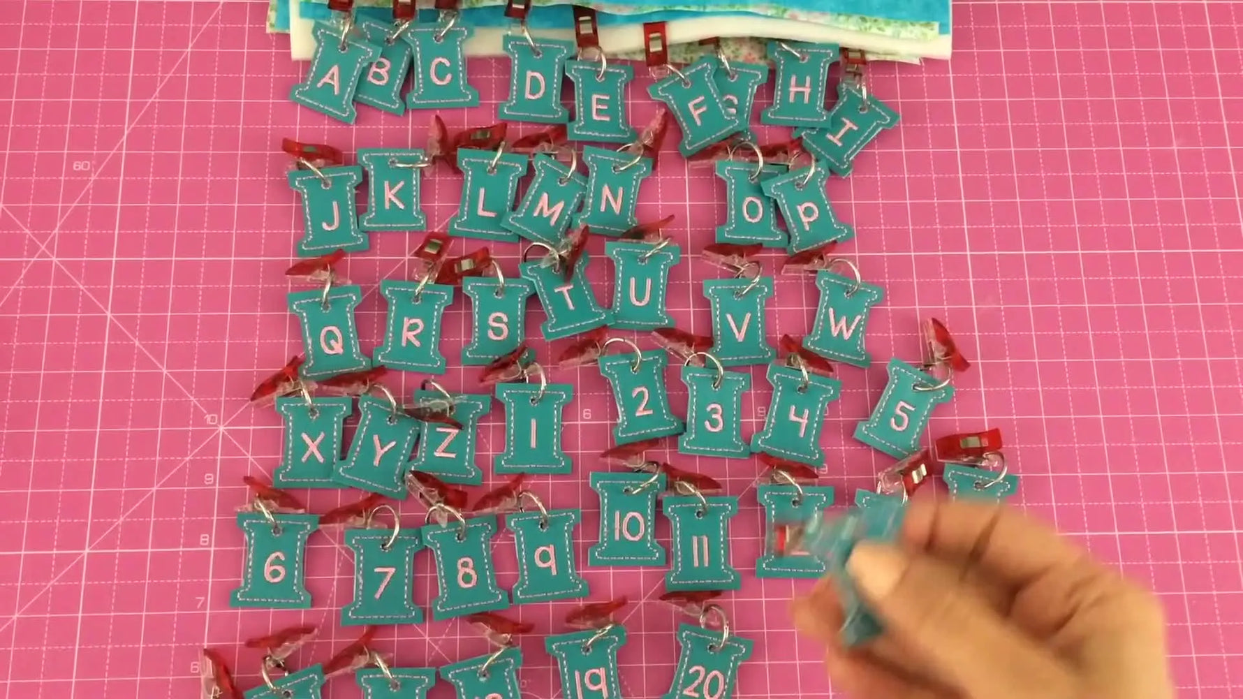 A close-up of a finished vinyl thread-spool tag with a crisp embroidered letter, ready to organize fabric bundles or tools.