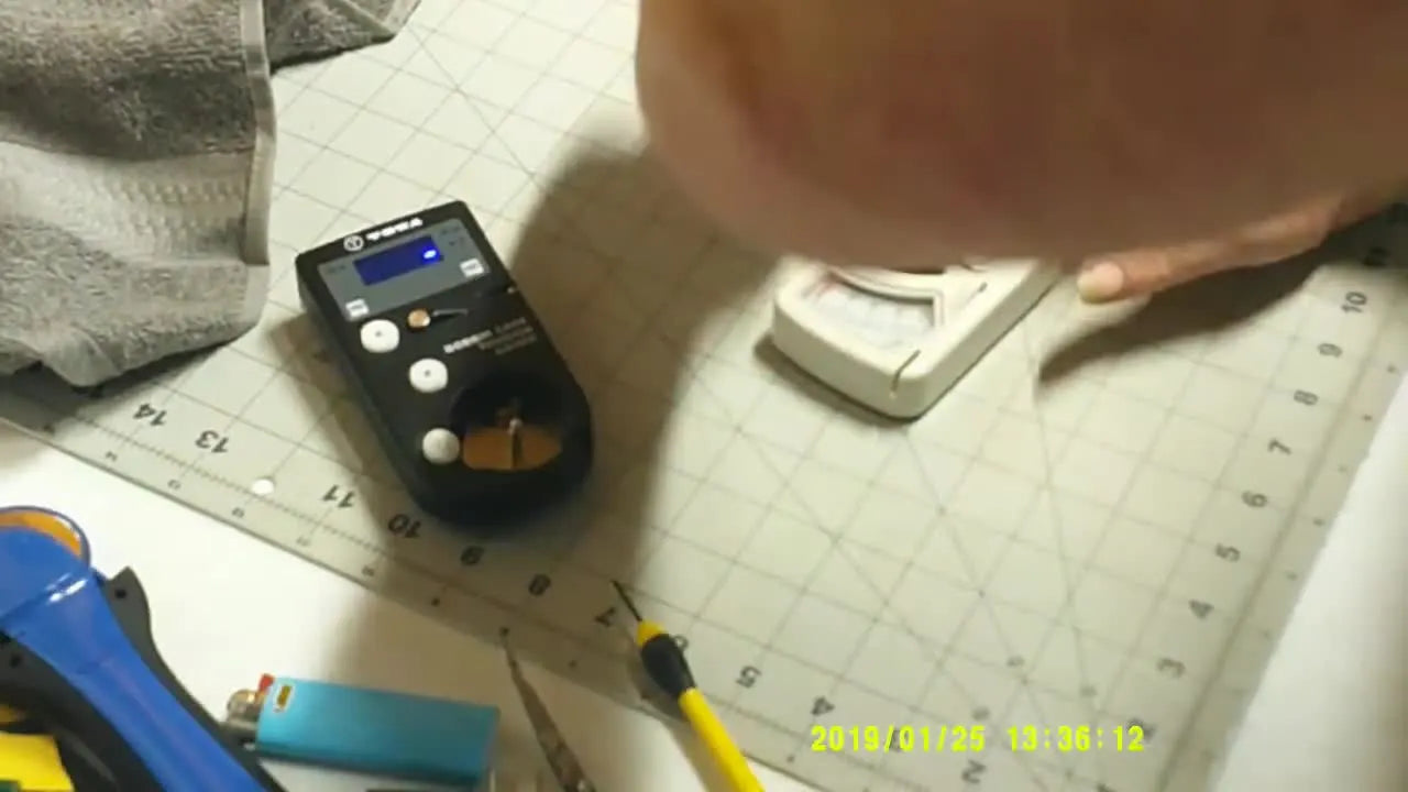 Hands threading the thread through the pulleys of a manual TOWA bobbin tension gauge for a stable, repeatable reading.