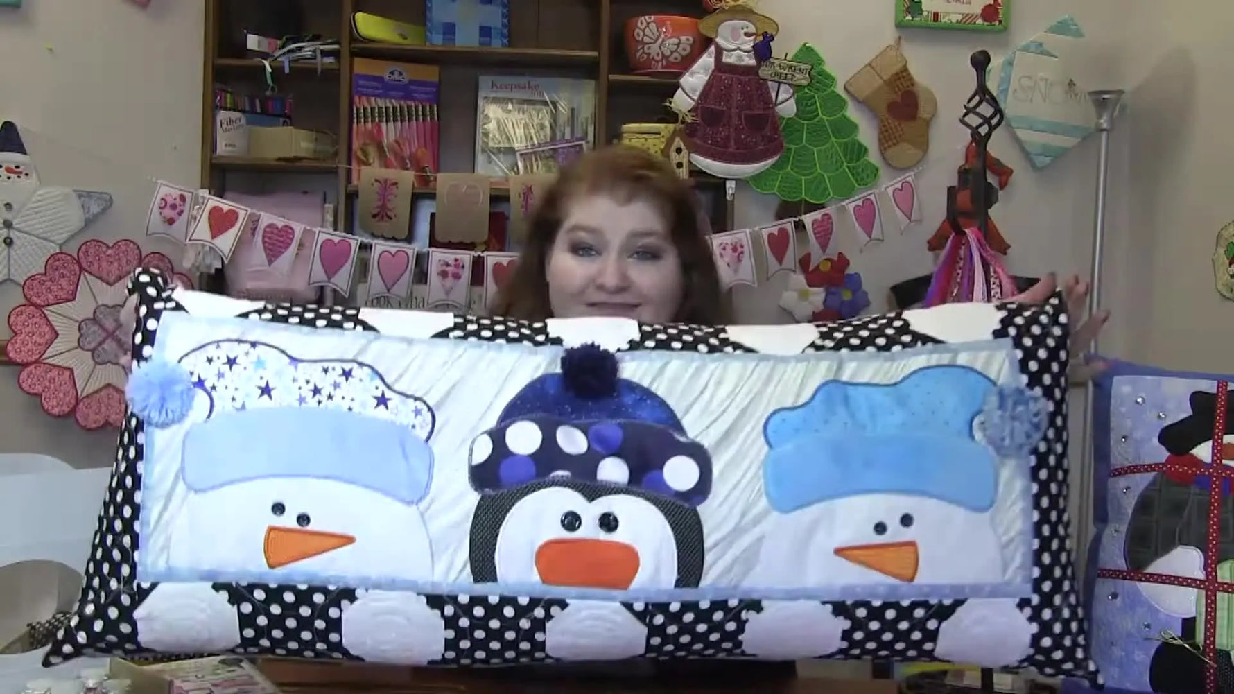 A full view of the Winter Whimsy bench pillow showing snowmen and penguins with fuzzy Minky applique hats and bright applique accents.